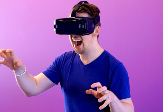 Man wearing virtual reality headset raising his hands.