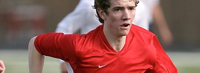 Man in soccer uniform running down a soccer pitch.